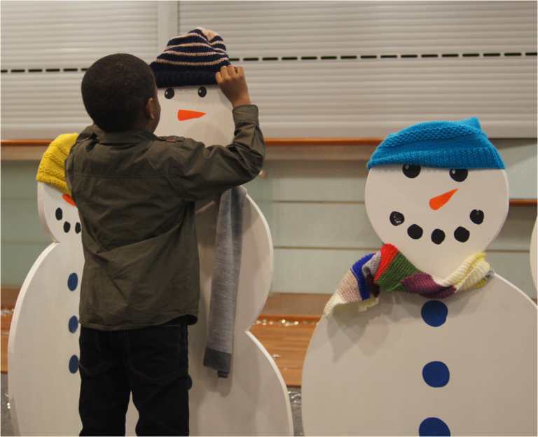 A child decorating a cardboard snowman