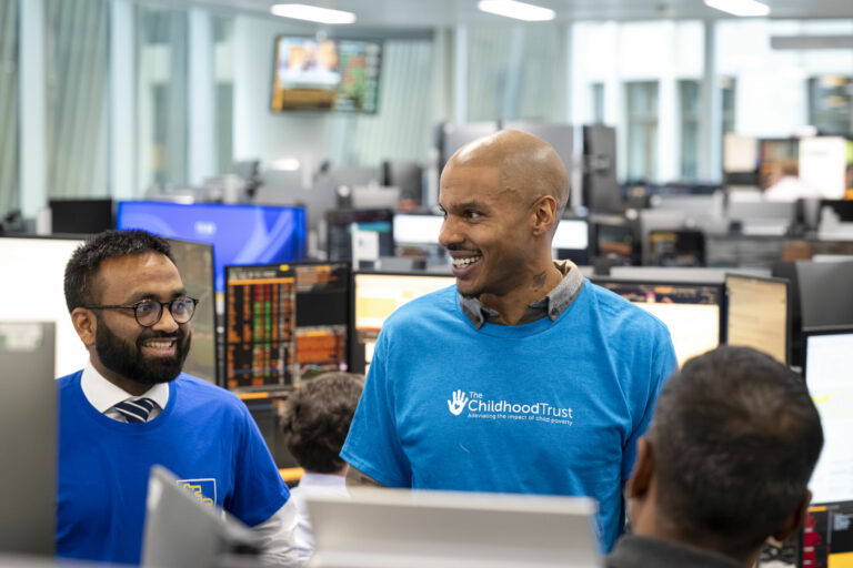 A person wearing a blue t-shirt with The Childhood Trust's logo